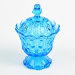 Compoteira em vidro translúcido na cor azul, lapidada com gomos no corpo e nas bordas. Apresenta discretos bicados na tampa. Altura e diâmetro: 19 x 13,5cm.