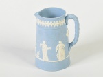 Jarra inglesa em faiança na cor azul, decorada com personagens e motivos florais em alto relevo na cor branca. Altura: 15cm.