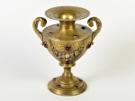 Ânfora em bronze dourado, ricamente cinzelada com motivos florais e aplicação de pedrarias. Altura: 22cm.