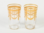 BACCARAT - Par de copos em cristal translúcido, decorado com guirlandas, e feras no tom dourado. Altura: 23,5cm.