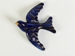 Escultura em porcelana representando andorinha, na cor azul escuro com realces dourados. Medidas: 16,5 x 13,5cm.