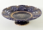 Centro de mesa faiança esmaltada e vitrificada na cor azul escuro, decorado com motivos floral ao centro e realces dourados. Marcação na base. Apresenta bicados. Altura e diâmetro: 9 x 30,5cm.