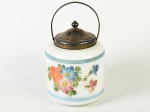 Antiga biscoiteira em vidro opalinado na cor branca, tampa em metal espessurado a prata. Decorada com motivos florais. Altura (sem a alça): 25cm.