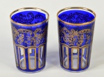 Par de copos em vidro veneziano na cor azul, decorados com guirlandas e realces dourados. Altura: 9,5cm.