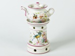 Bule para chá com coluna para aquecimento, em porcelana francesa esmaltada e vitrificada na cor branca, decorados com motivos florias e fauna. Tampa do bule apresenta bicado. Altura total do conjunto 23cm.
