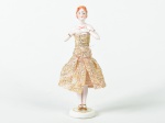 Boneca em porcelana esmaltada e vitrificada, vestido em tecido na cor bege. Altura: 14cm.
