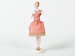 Boneca em porcelana esmaltada e vitrificada, vestido na cor salmão. Altura: 16cm.