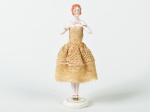 Boneca em porcelana esmaltada e vitrificada, vestido na cor bege. Altura: 15,5cm.