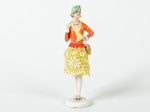 Boneca em porcelana esmaltada e vitrificada, saia em tecido na cor verde. Altura: 16cm.