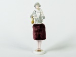Boneca em porcelana esmaltada e vitrificada, saia em tecido na cor vinho. Altura: 17cm.
