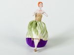 Boneca em porcelana esmaltada e vitrificada, saia em tecido na cor verde. Altura: 13,5cm.