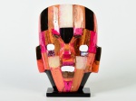 Escultura em colagem de placas de pedra multicoloridas esmaltadas, no formato de máscara cerimonial. Medidas: 21 x 16 x 8cm.