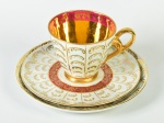 PARANÁ - Conjunto de xícara para chá, pires e pratinho para sobremesa, em porcelana esmaltada e vitrificada iridescente, com realces dourados. Interior da xícara dourada com faixa vermelha e motivos florais. Altura da xícara: 8cm; Diâmetro do pratinho: 19cm.
