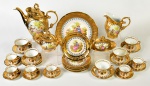 Serviço para chá e café em porcelana esmaltada e vitrificada na cor dourada, realçado com motivos florais, decoração de cena galante. Composto por 1 bule, 1 leiteira, 1 açucareiro, 1 manteigueira, 5 xícaras para chá com pires, 6 xícaras para café com pires, 1 prato para bolo, 6 pratos para sobremesa. Total de 22 peças.