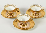 DP - Conjunto de 3 xícaras para café e pires, em porcelana esmaltada e vitrificada na cor dourada, realçada com motivos florais e decoração de cena galante. Altura da xícara: 4,5cm.