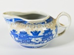 Leiteira em porcelana oriental esmaltada e vitrificada na cor branca, decorado com cenas de paisagem e pagodes. Necessita de limpeza. Altura: 7cm.