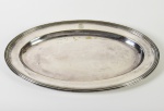 CHRISTOFLE - Travessa oval em metal espessurado a prata, com monograma. Apresenta pequenos danos no banho próximo ao monograma. Contrastado e numerado na base. Medidas: 3 x 49 x 32cm.