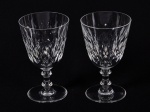BACCARAT - Par de taças para água em cristal translúcido, com fina lapidação de losangos em relevo. 1 taça apresenta discretos bicados na borda. Altura: 15cm.