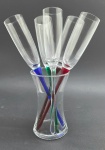 Conjunto com 05 taças de cristal para espumante; pé alto, com hastes de diferentes cores e sem base circular; inseridas em vaso curvo acinturado em cristal, que lhes serve de suporte. Medidas: 32 x 5 cm (taças); 17 x 10 cm (vaso).
