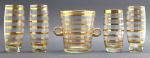 Conjunto composto por 01 balde para gelo e 04 copos abaulados, adornados com faixas e filetes dourados em paralelo. Em cristal. Um dos copos com tamanho, base e decoração diferente dos demais. Medidas: 16 x 13 cm; 15 x 7 cm; 14 x 7 cm.