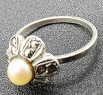 ANEL - Anel em prata, peso total: 2 g; com detalhe floral adornado com marcassitas e uma pérola no centro. Medidas: 1,8 cm (aprox.)