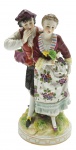 Grupo escultórico com a representação de um casal em trajes de época; em porcelana multicolorida. Medidas: 17 x 9 cm. Marca de manufatura não identificada.