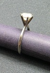ANEL DE OURO BRANCO, 3g - Anel de ouro branco, pesando 3g no total, textura lisa com uma pequena pedra translúcida no topo. Medida: 2cm de diâmetro.