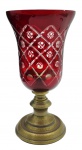 Vaso em cristal no estilo taça, na cor rubi e lapidado com elementos circulares e losangulares; base pedestal em metal. Medidas: 33 x 17 cm. Pintura rubi com ínfimo ponto de desgaste na borda; metal com desgastes no cromado.