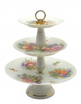 SALER - Bandeja tripla para doces, com pratos adornados com coloridos motivos frutais, e faixas e filetes dourados; alça superior em metal cromado; base pedestal. Em porcelana. Medidas: 34 x 27 cm. Metal com desgastes no cromado. Filete dourado na borda dos pratos desvanecido.