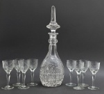 01 licoreira e 08 taças de licor, com diferentes padrões decorativos: licoreira com tampa pontiaguda e multifacetada, e corpo ovóide lapidado com motivos frutais e caneluras; e taças adornadas com motivos vegetalistas e linhas paralelas. Em cristal translúcido. Medidas: 38 x 12 cm; 12 x 5 cm. Ínfimos bicados na base da tampa da licooreira.