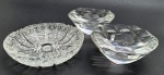 03 cinzeiros circulares em cristal translúcido, sendo dois de mesmo modelo; com diferentes formatos e padrões decorativos. Medidas: 15 x 4 cm; 12 x 5 cm.