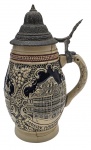 TANKARD - Tankard, caneca de chopp/cerveja, com tampa em metal; em cerâmica esmaltada e em relevo, no estilo tradicional alemão, com rica policromia retratando pontos turísticos gastronômicos franceses na cidade de Estrasburgo. Medidas: 22 x 14 cm. Com sinais de restauro; tampa em metal com desgastes.