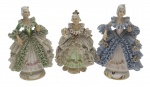 PORCELANA REBIS - 03 bibelôs representando damas em trajes de época, sendo os corpos em porcelana, e os vestidos rendados moldados através de uma técnica que envolve mergulhar um tecido de algodão na barbotina (massa líquida da porcelana). Em porcelana multicolorida. Medidas: 12 x 8 cm. Rendas com danos em alguns locais; ínfimos bicados em alguns pontos.