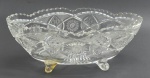 Centro de mesa oval em robusto cristal translúcido lapidado com borda serrilhada, caneluras, e detalhes fitomórficos e geométricos; com quatro pés em forma de volutas. Medidas: 37,5 x 18,5 cm. Um dos pés com sinais de restauro; um dos pés com dano.