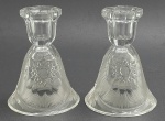 Par de castiçais em cristal translúcido com base tipo campânula adornada com padrões estelares, fitomórficos e ranhuras. Medidas: 13 x 9,5 cm. Um dos castiçais com sinais de restauro na borda.