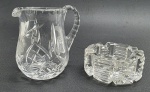 01 cinzeiro e 01 jarra decorativa em cristal translúcido e com diferentes padrões decorativos. Medidas: 8 x 3 cm; 10 x 9 cm.