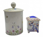 SALER - 02 diferentes potiches em porcelana, sendo um da manufatura Saler, no formato cilíndrico, adornado com coloridos motivos florais, vegetalistas, borboletas e abelhas, e filetes dourados na tampa; e o outro no formato retangular decorado com coloridas volutas, motivos florais e vegetalistas, pintados à mão, e assinado pela artista (sem marca de manufatura). Medidas: 25 x 16 cm; 13 x 11 cm. Filete dourado da tampa do potiche Saler desvanecido em alguns pontos.