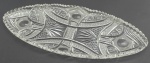 Travessa elíptica em cristal translúcido, com borda serrilhada; lapidada com padrões fitomórficos, estelares e geométricos. Medidas: 54 x 21 cm.
