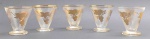 05 taças de cristal incolor, no formato cônico, decoradas em dourado com filetes e padrões frutais e vegetalistas em dourado; cristal com acabamento texturizado. Medidas: 8 x 8 cm. Filetes dourados da borda ligeiramente desvanecidos.