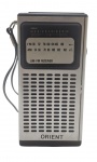 ORIENT - RÁDIO PORTÁTIL - Antigo rádio portátil de bolso AM-FM em design vertical com acabamento prateado. Funcionamento por pilhas. Medida: 14cm. Não testado, possui ínfimos desgastes e necessita reparo no botão giratório lateral do seletor.