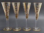 04 taças com corpo no formato cônico e adornado com volutas, faixas e filetes em dourado; pé alto; em cristal translúcido. Medidas: 24 x 7 cm. Douração na borda e na base desvanecida em ínfimos pontos.