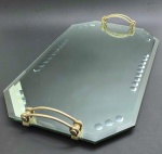 Bandeja espelhada no formato octogonal, com alças laterais duplas em metal curvo. Espelho com acabamento bisotado e decorado com padrões circulares. Apoiada sobre quatro pequenas esferas metálicas. Medidas: 61 x 38 x 7,5 cm. Espelho com ínfimas manchas.