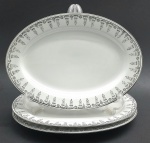 JINGDEZHEN, MADE IN CHINA - Parte de serviço de jantar em porcelana com 03 travessas ovais de mesmo tamanho, decoradas na borda com arabescos e motivos florais na cor preta e filetes prateados. Fabricação chinesa, na cidade de Jingdezhen, mundialmente famosa por sua produção de porcelana. Medidas: 31 x 22 cm.