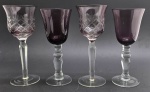 04 taças de cristal na cor vinho, sendo duas em tom mais claro, lapidadas com padrões fitomórficos e losangulares e hastes facetadas; taças na cor vinho mais escura com hastes boleadas. Medidas: 19,5 x 8 cm; 20,5 x 8 cm.
