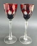 02 taças em cristal double na cor rubi, lapidadas com elementos ovais; pé alto com haste multifacetada. Medidas: 23 x 8,5 cm.