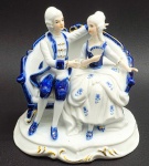 CDC HANDMADE ROKOKO 1720-80 - Bibelô com a representação de uma figura masculina e uma feminina em trajes de época, sentadas em sum sofá; em porcelana com detalhes em azul cobalto e dourado. Medidas: 16 x 16 x 12 cm. Fabricado no Sri Lanka.