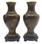 Par de antigos vasos no formato balaústre, de temática oriental; em bronze esmaltado e policromado com motivos florais através da técnica de cloisonné; interior esmaltado na cor azul cobalto. Sobre base circular de madeira. Medidas: 25 x 10 cm.