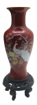 Vaso balaústre de temática oriental na cor vinho, com filete dourado na borda; galeria central multicolorida retratando um pássaro em meio a um jardim; em porcelana; sobre base de madeira com volutas vazadas e cinco pernas curvas; fabricação chinesa. Medidas: 41 x 13 cm. Pintura vinho com ínfimos danos na borda e na base.