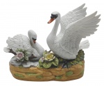 ROYAL CROWN - Grupo escultórico com caixa de música acoplada, representando um casal de cisnes brancos; caixa de música com alavanca deslizante; em biscuit policromado. Medidas: 27 x 20 x 10 cm. Algumas flores com ínfimos bicados; cauda de um dos cisnes com ínfimo dano; asa de um dos cisnes com ínfimo dano; caixa de música inoperante.