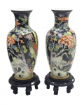 Par de vasos no formato balaústre e com temática oriental, decorados com pássaros, flores e folhagens; em porcelana policromada; apoiados sobre bases circulares de madeira com volutas vazadas e cinco pés curvos; fabricação chinesa. Medidas: 47 x 15 cm.